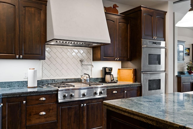 kitchen featuring dark brown cabinetry, premium range hood, appliances with stainless steel finishes, and tasteful backsplash