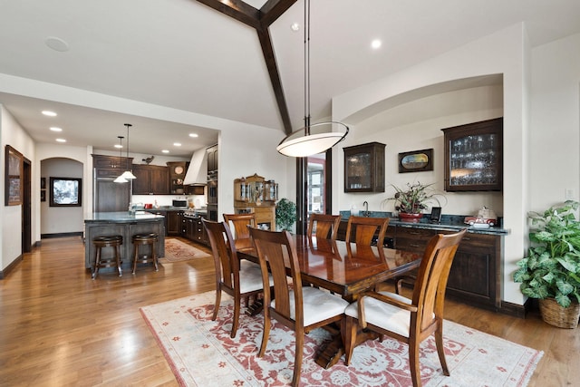 dining space featuring lofted ceiling with beams and light hardwood / wood-style floors