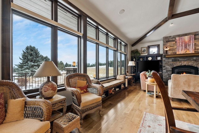 living area featuring beamed ceiling, a stone fireplace, high vaulted ceiling, and light hardwood / wood-style flooring