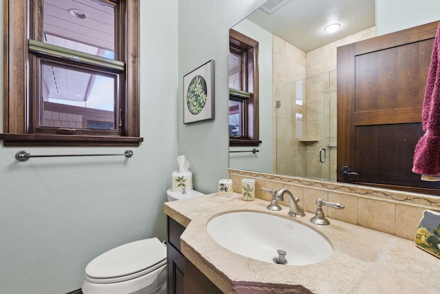 bathroom featuring decorative backsplash, vanity, an enclosed shower, and toilet