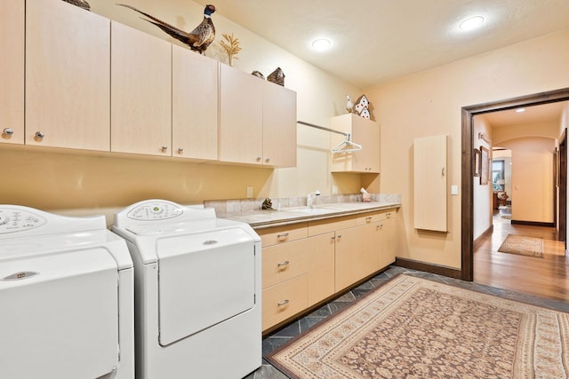 clothes washing area featuring cabinets, washer and dryer, dark wood-type flooring, and sink