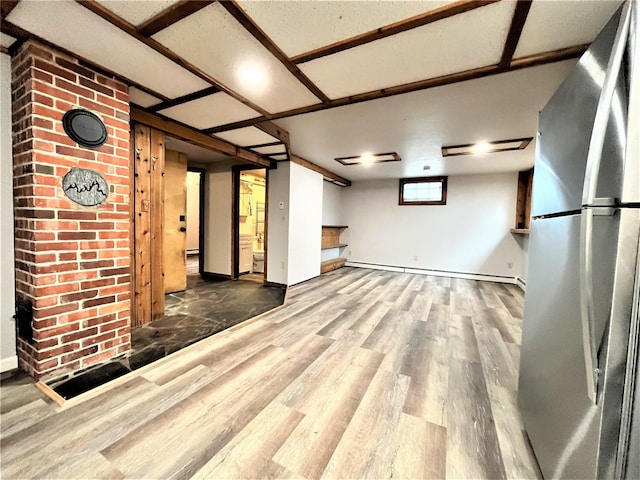 unfurnished living room featuring hardwood / wood-style floors and a baseboard heating unit