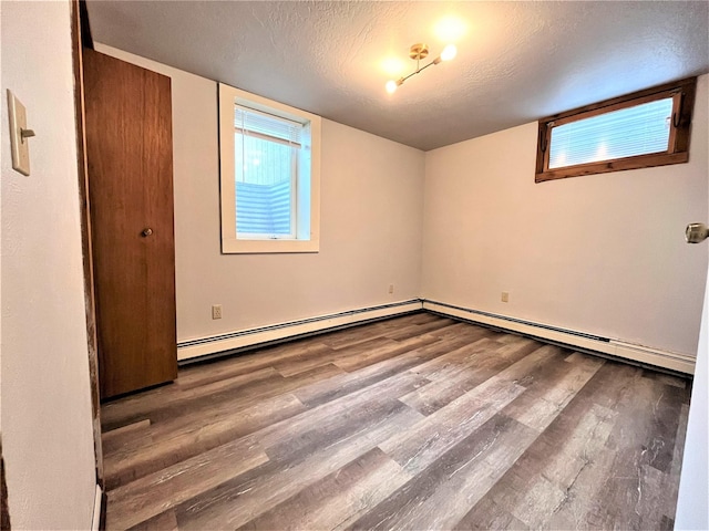 unfurnished room featuring a baseboard radiator, wood-type flooring, and a textured ceiling