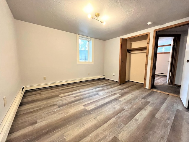 unfurnished bedroom with a textured ceiling, a baseboard radiator, and hardwood / wood-style flooring