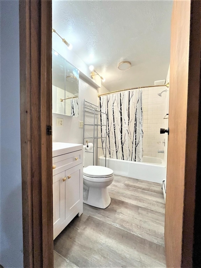 full bathroom featuring vanity, hardwood / wood-style flooring, toilet, a textured ceiling, and shower / tub combo