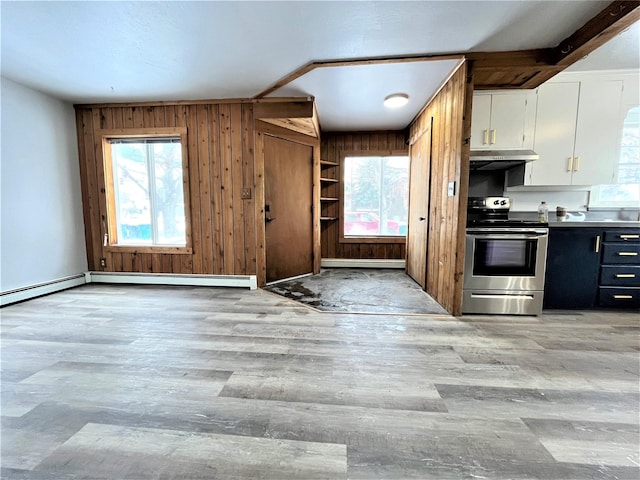 kitchen featuring stainless steel range with electric stovetop, a healthy amount of sunlight, white cabinets, and wood walls