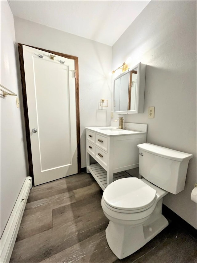 bathroom featuring baseboard heating, toilet, vanity, and hardwood / wood-style flooring