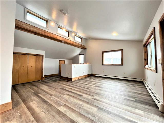 unfurnished living room with hardwood / wood-style floors, lofted ceiling, and a baseboard radiator