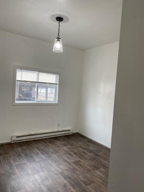 spare room featuring dark hardwood / wood-style flooring and a baseboard heating unit