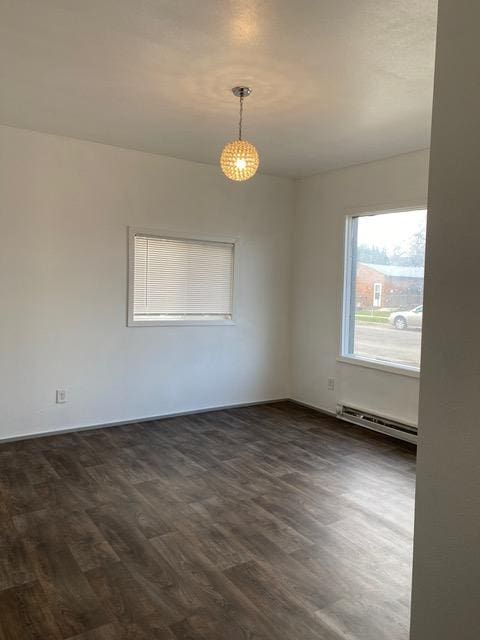 spare room featuring baseboard heating and dark hardwood / wood-style flooring