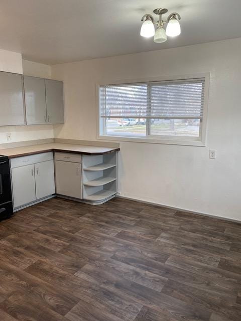 kitchen with black range oven, dark wood-type flooring, and an inviting chandelier