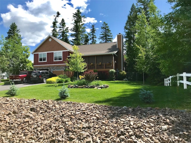 rear view of property featuring an attached garage, driveway, a yard, and fence