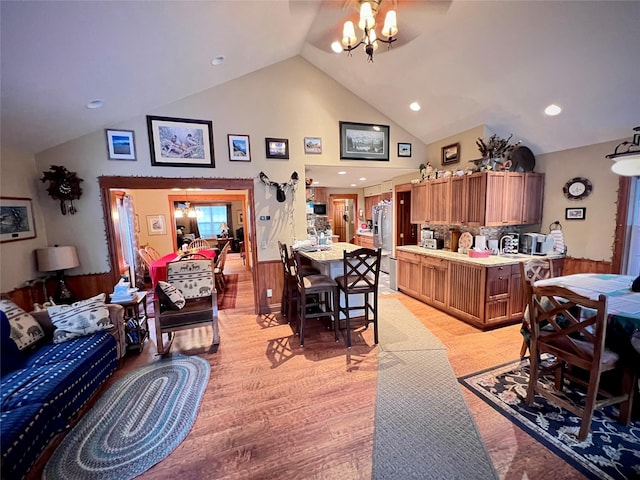 living room featuring sink, high vaulted ceiling, light wood-type flooring, and a notable chandelier