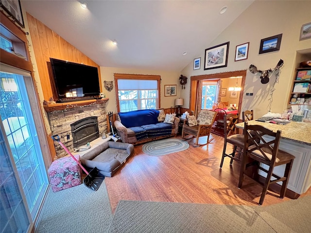 living room featuring a fireplace, high vaulted ceiling, and light hardwood / wood-style flooring