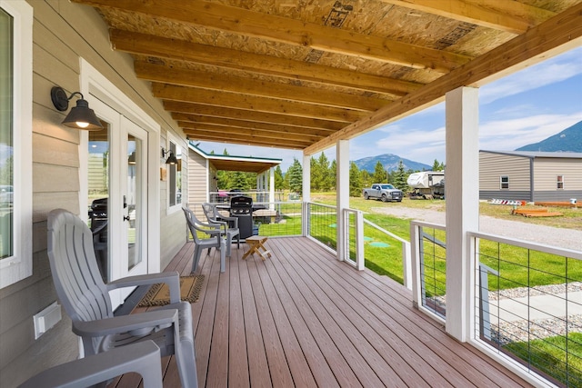 wooden deck featuring a mountain view, covered porch, and grilling area