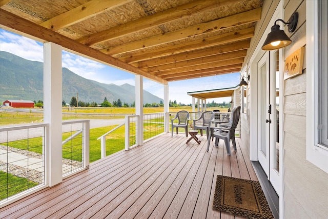 deck with a mountain view, covered porch, and a rural view