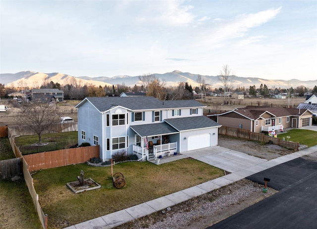 view of front of home featuring a mountain view, a front lawn, covered porch, and a garage