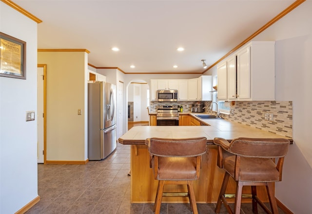 kitchen featuring sink, kitchen peninsula, a breakfast bar area, white cabinetry, and stainless steel appliances