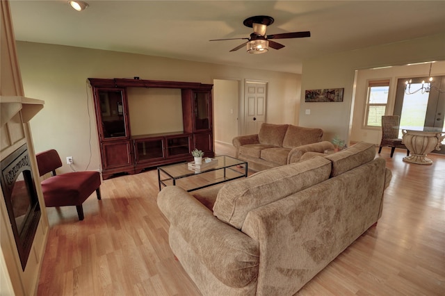 living room featuring ceiling fan with notable chandelier and light hardwood / wood-style floors