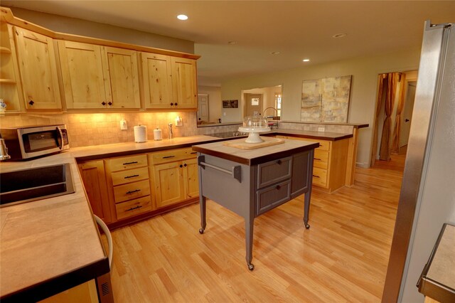 kitchen with light brown cabinetry, wood counters, and kitchen peninsula