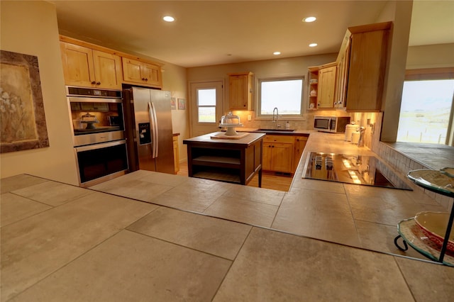 kitchen featuring sink, tile counters, kitchen peninsula, stainless steel appliances, and light brown cabinets