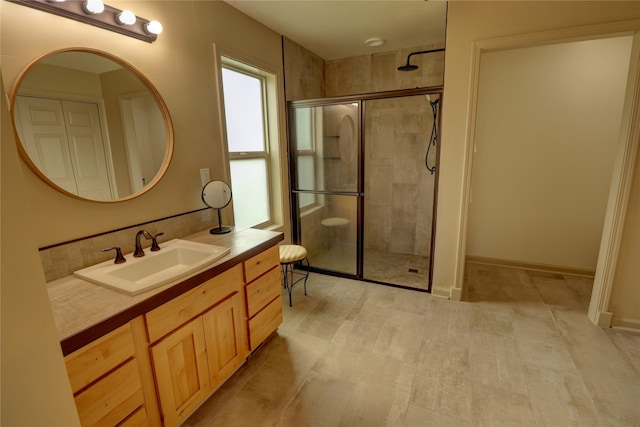 bathroom with vanity, a shower with shower door, and decorative backsplash