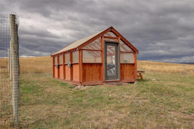 view of outdoor structure with a lawn and a rural view