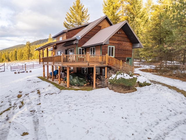 snow covered rear of property featuring a wooden deck