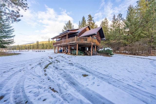 snow covered rear of property featuring a deck