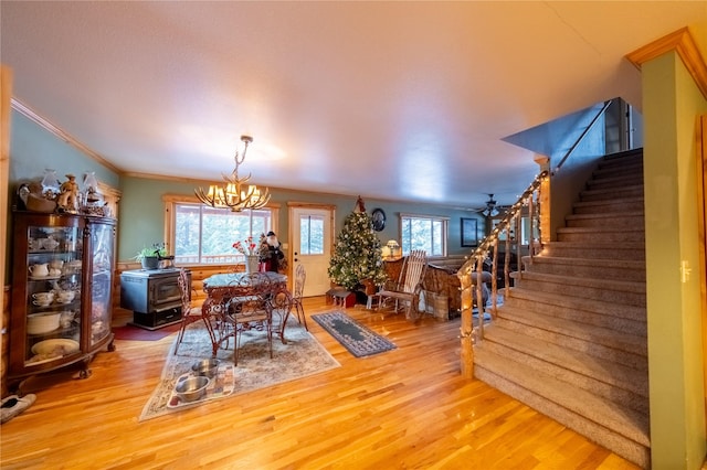 dining space with a chandelier, hardwood / wood-style flooring, a wood stove, and a wealth of natural light