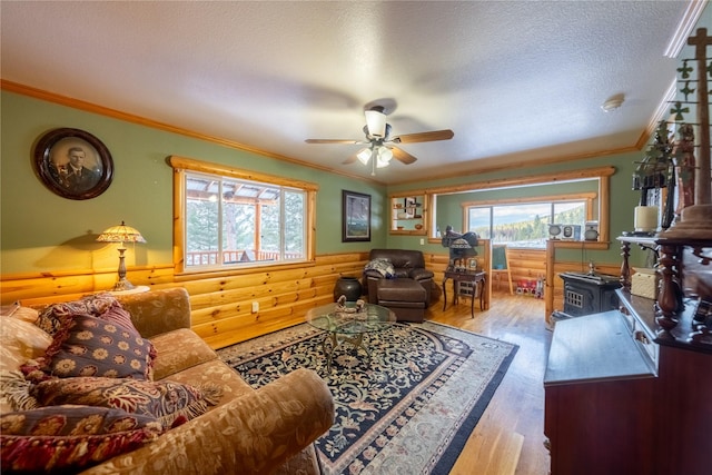 living room featuring crown molding, light hardwood / wood-style flooring, ceiling fan, and a textured ceiling