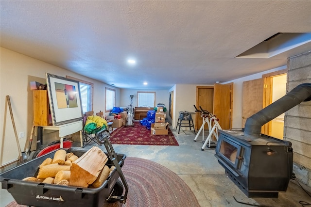 game room featuring a wood stove, concrete floors, and a textured ceiling