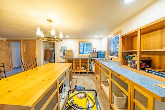 kitchen with butcher block counters, sink, a center island, an inviting chandelier, and pendant lighting