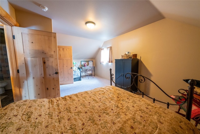 unfurnished bedroom featuring ensuite bathroom, light carpet, and vaulted ceiling