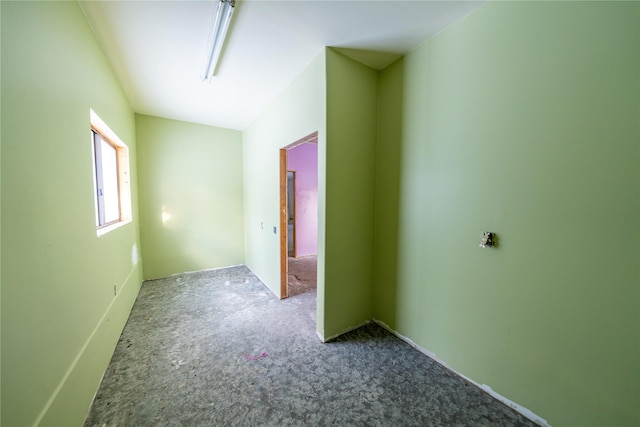 carpeted spare room with vaulted ceiling