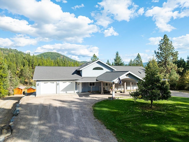 view of front of home with a mountain view, covered porch, a front yard, and a garage