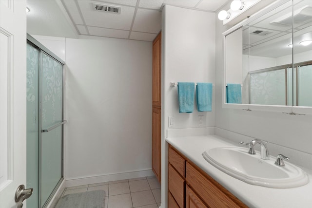 bathroom with tile patterned floors, vanity, a drop ceiling, and a shower with shower door