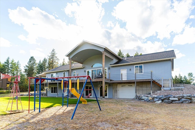 rear view of property featuring a playground, a lawn, and a garage