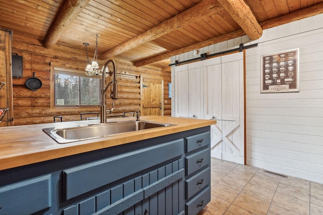 kitchen with beam ceiling, butcher block counters, wooden ceiling, a barn door, and decorative light fixtures