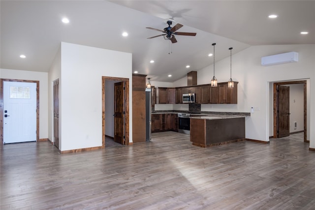 kitchen with a wall mounted AC, hardwood / wood-style floors, high vaulted ceiling, and appliances with stainless steel finishes