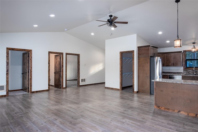 kitchen featuring light stone countertops, dark hardwood / wood-style flooring, dark brown cabinetry, vaulted ceiling, and decorative light fixtures