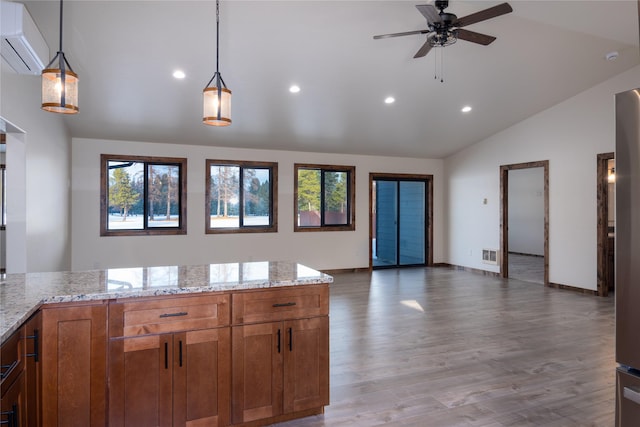 kitchen with a wall mounted AC, light stone counters, light hardwood / wood-style flooring, and decorative light fixtures