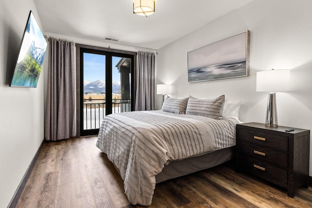 bedroom featuring access to exterior, wood finished floors, and baseboards