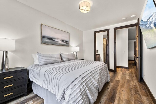 bedroom featuring dark wood finished floors, baseboards, and connected bathroom