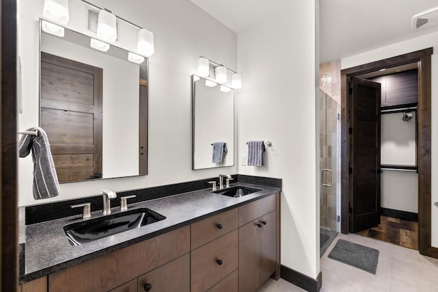 full bathroom featuring a stall shower, baseboards, and double vanity