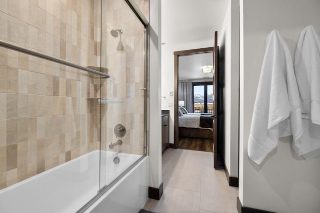 ensuite bathroom with shower / bath combination with glass door, tile patterned flooring, and baseboards