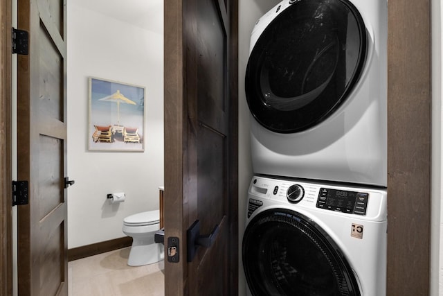 washroom with stacked washing machine and dryer and baseboards