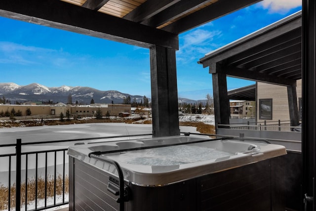 snow covered deck with a hot tub and a mountain view
