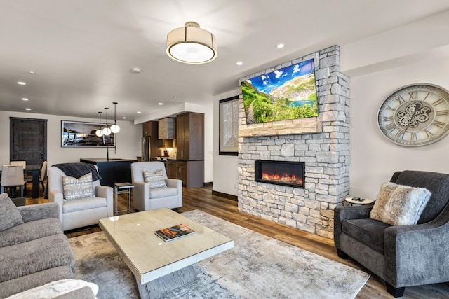living room featuring dark wood-type flooring, a fireplace, recessed lighting, and baseboards