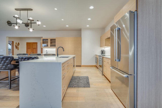 kitchen featuring sink, an island with sink, decorative light fixtures, stainless steel appliances, and a chandelier